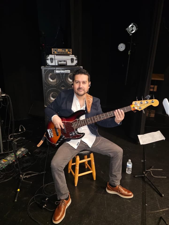 Bajista sentado en el escenario con su bajo sunburst