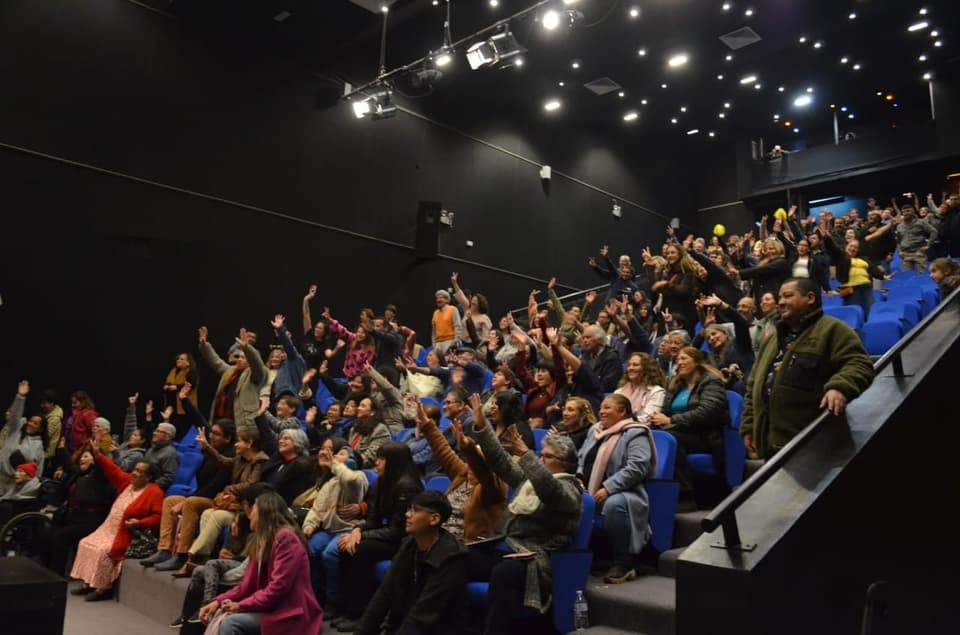 Público de un teatro con los brazos en alto